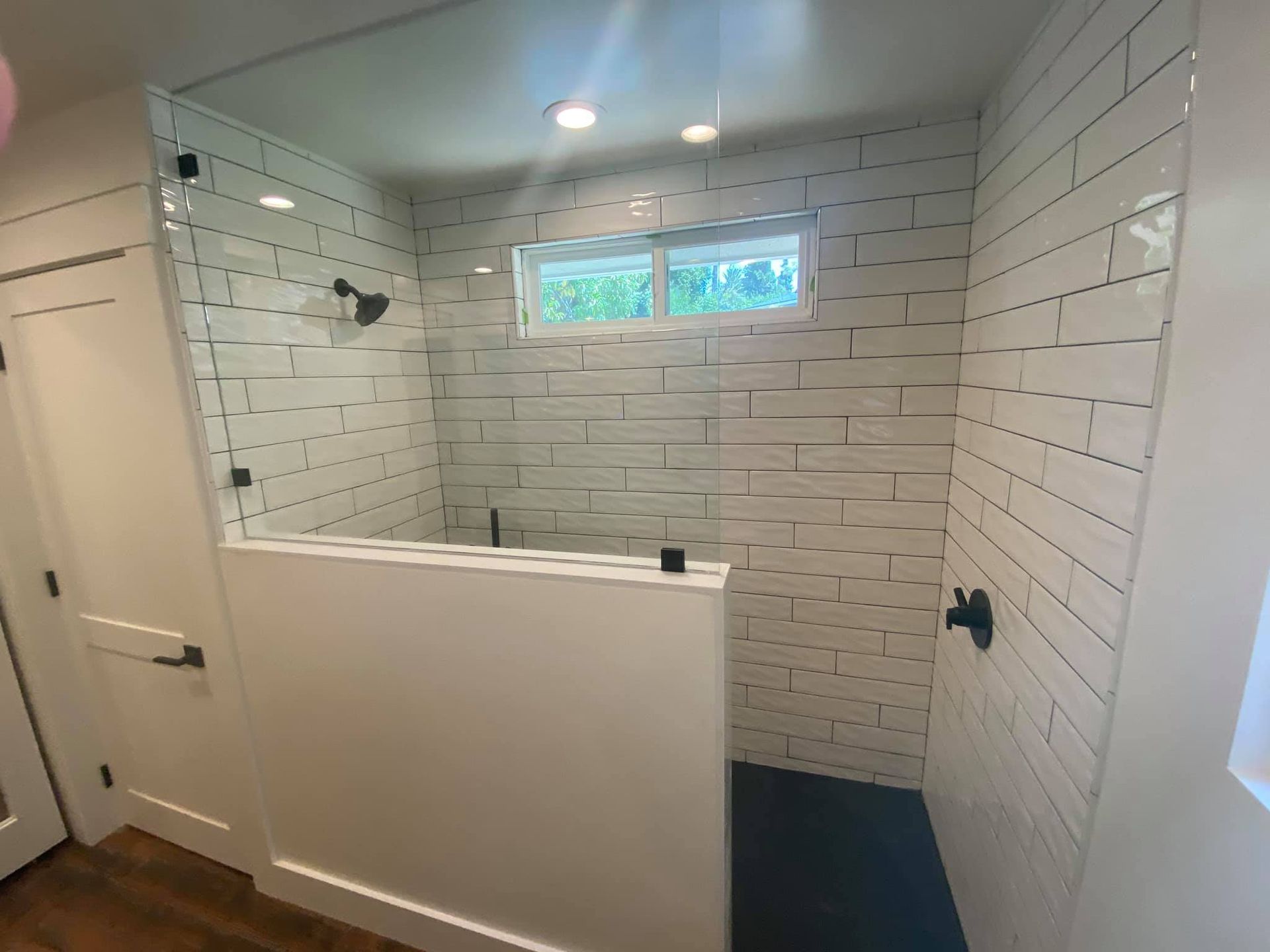 A bathroom with white tiles and a walk in shower