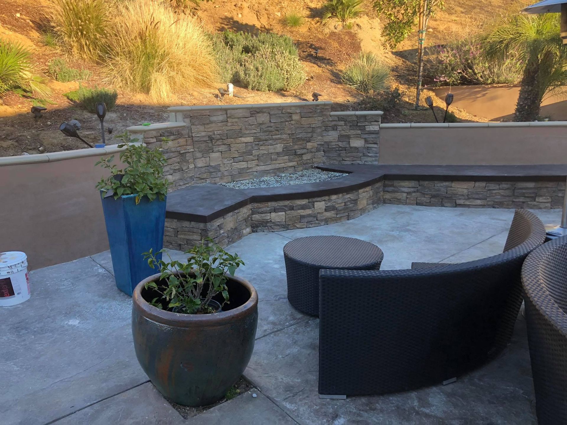 A patio with a stone wall and a potted plant