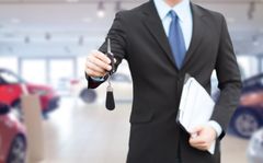 Finance broker handing over key to new car loan purchase