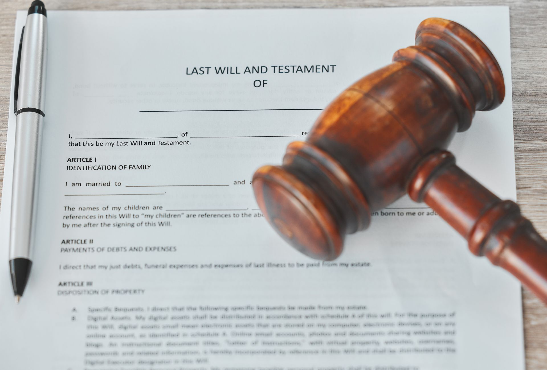 A wooden judge 's gavel is sitting on top of a last will and testament.