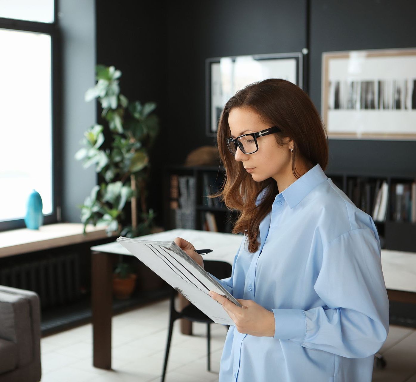 A woman is standing in a living room looking at a piece of paper.