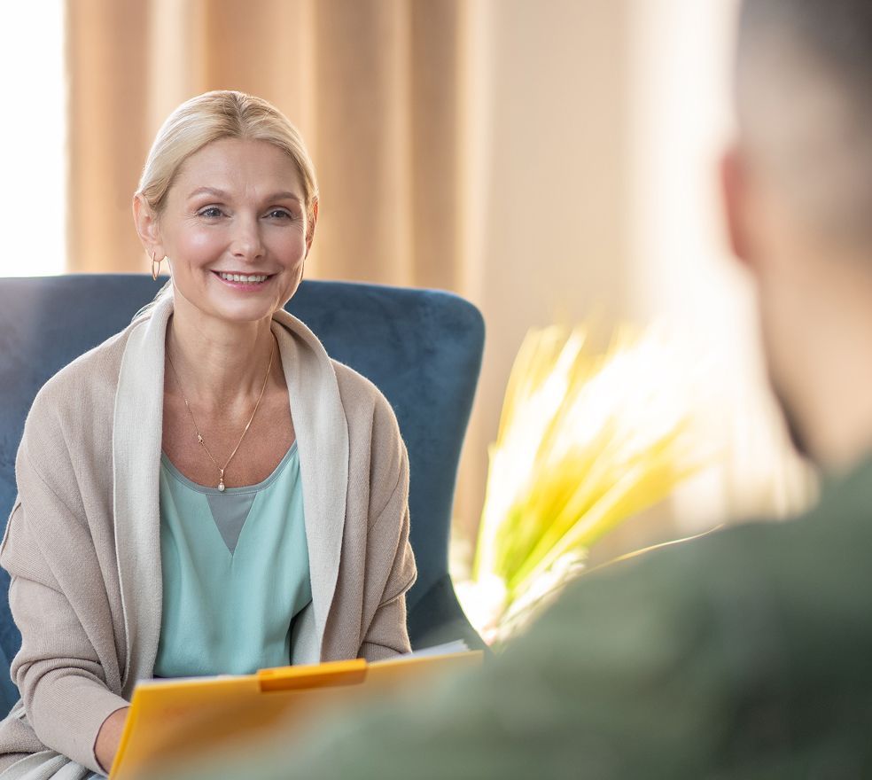 A woman is sitting in a chair talking to a man.