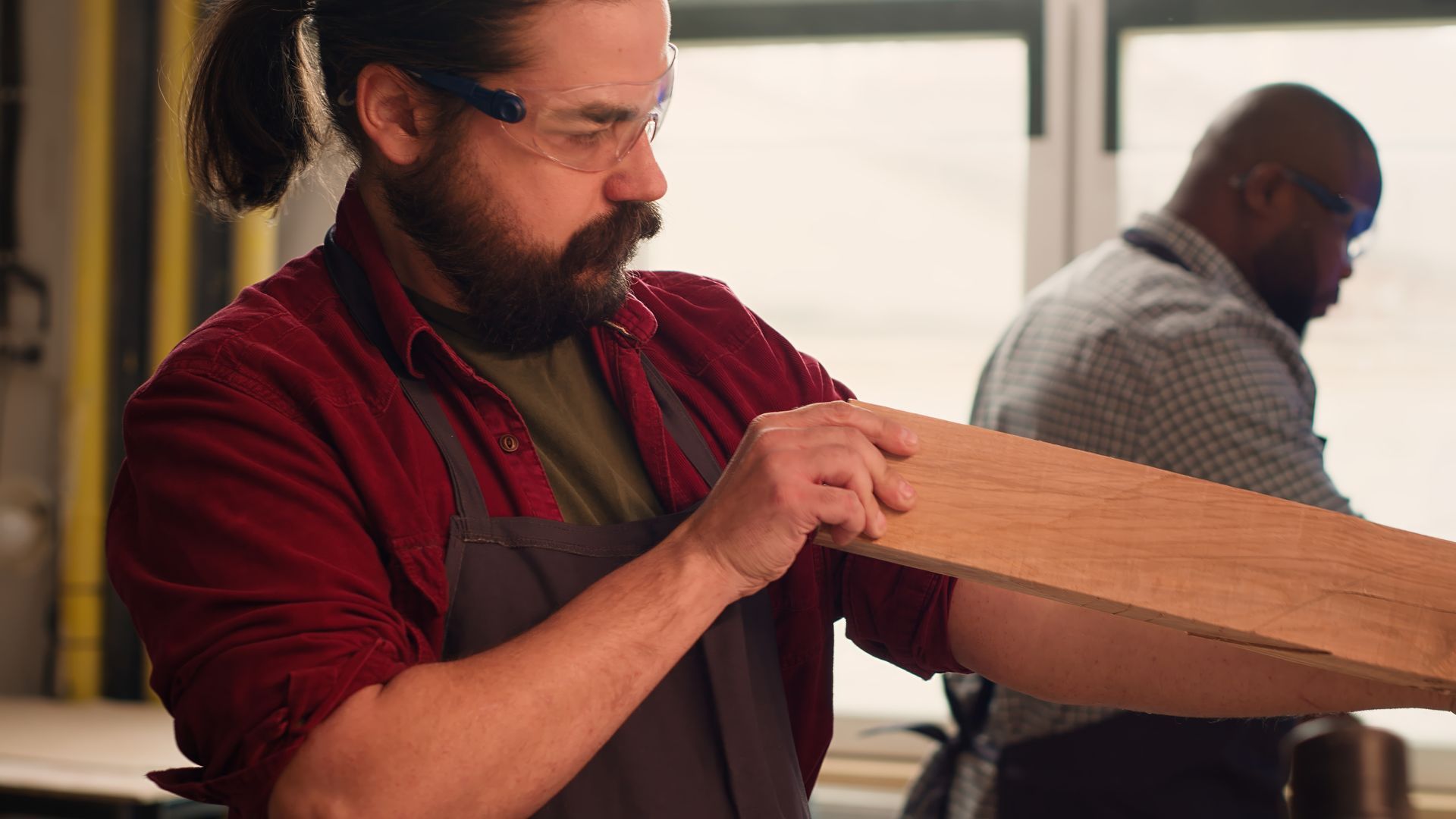 A man is holding a piece of wood in his hands in a workshop.