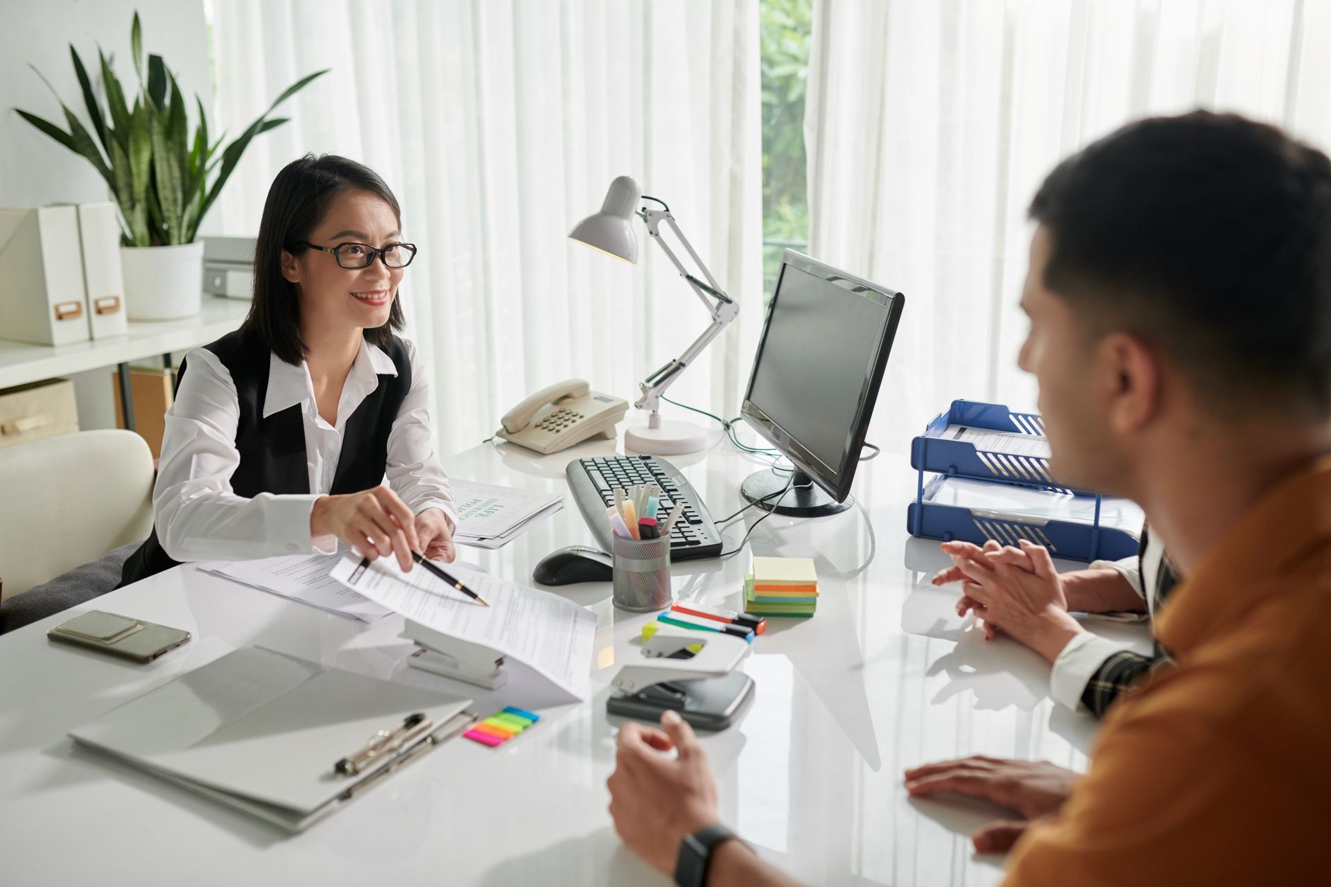 A woman is sitting at a desk talking to a man.