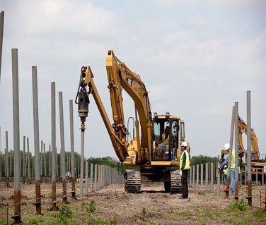 Excavator putting down fence posts