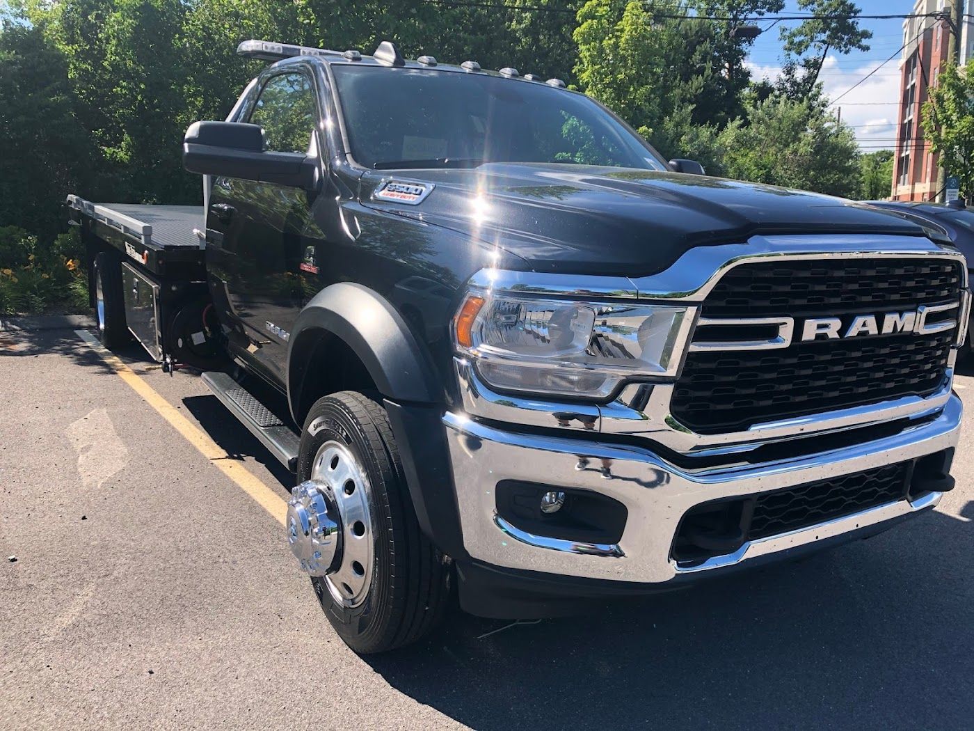 Black Ram 5500 flatbed truck parked outside on a sunny day.