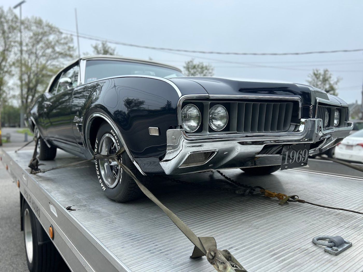 Black classic car secured on a flatbed tow truck.