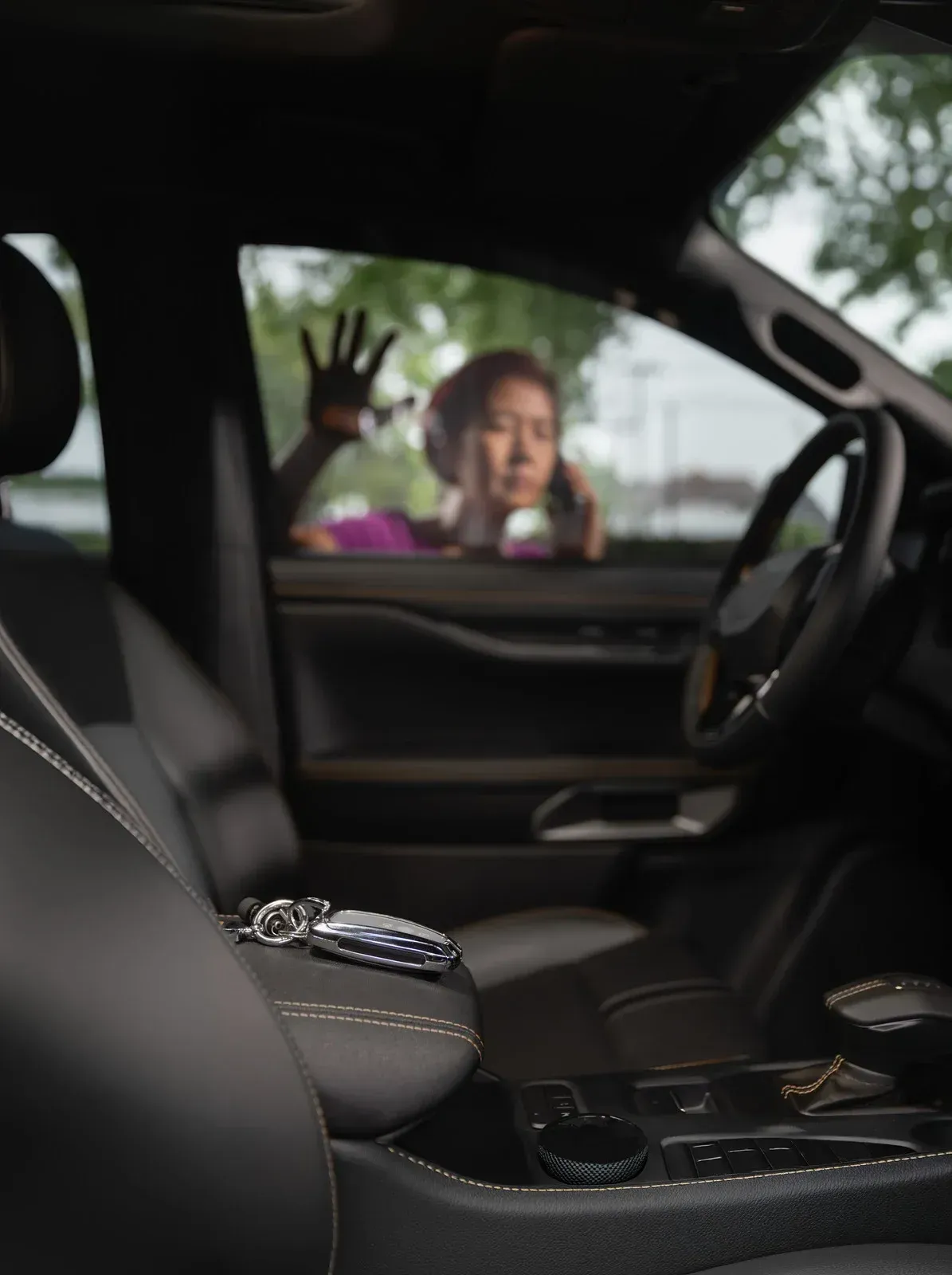 Keys on car console with person locked out, reaching for help through window.
