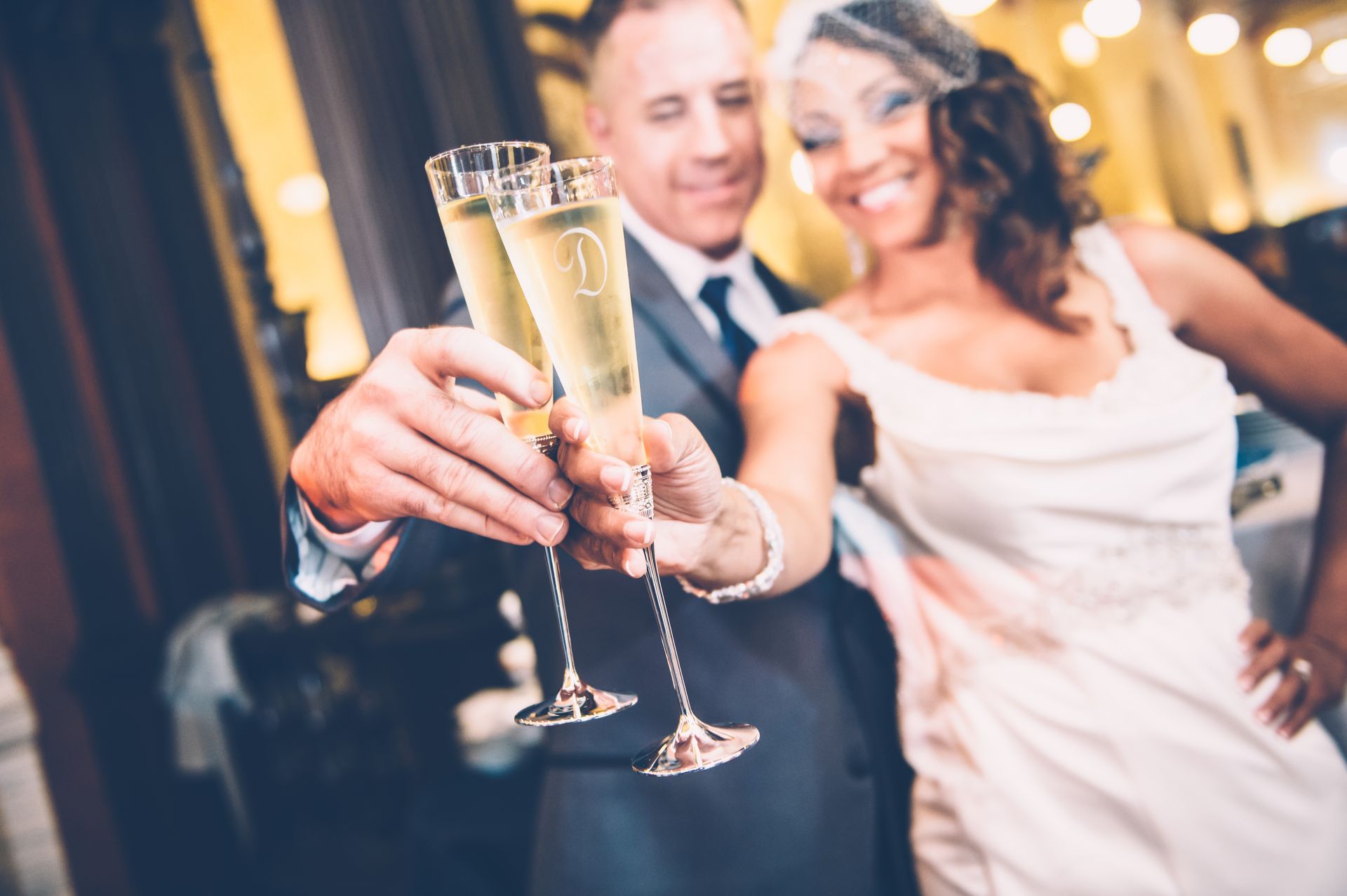Couple toasting with champagne glasses at a wedding reception; smiling.