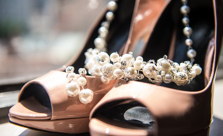 Pink platform high heels with a pearl necklace draped across them.