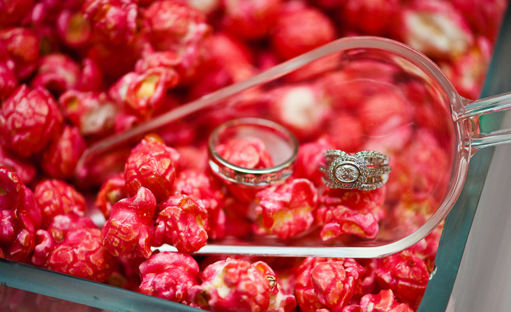 Two wedding rings on red popcorn in a scoop, inside a container.