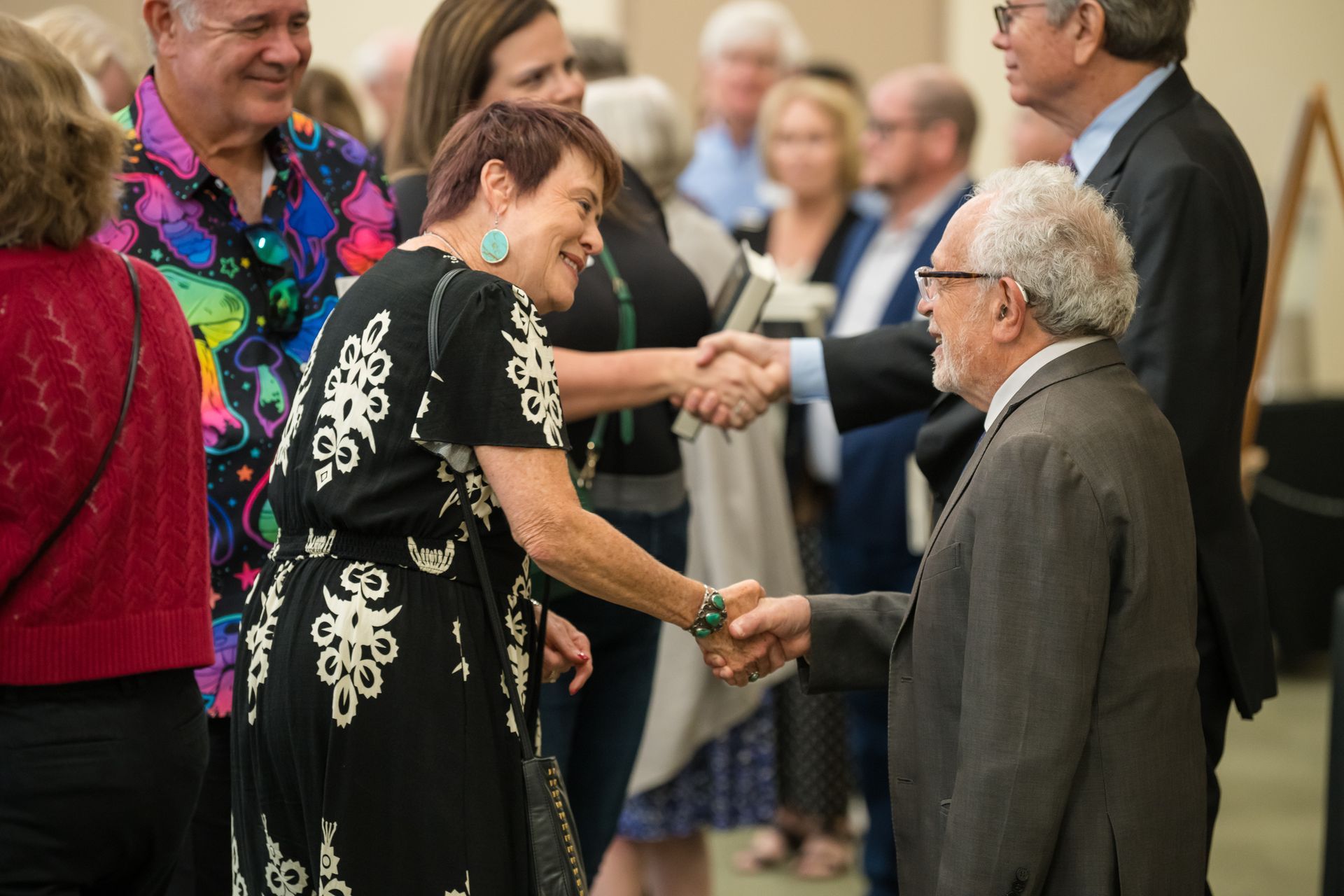 People shaking hands at an event, inside a building.