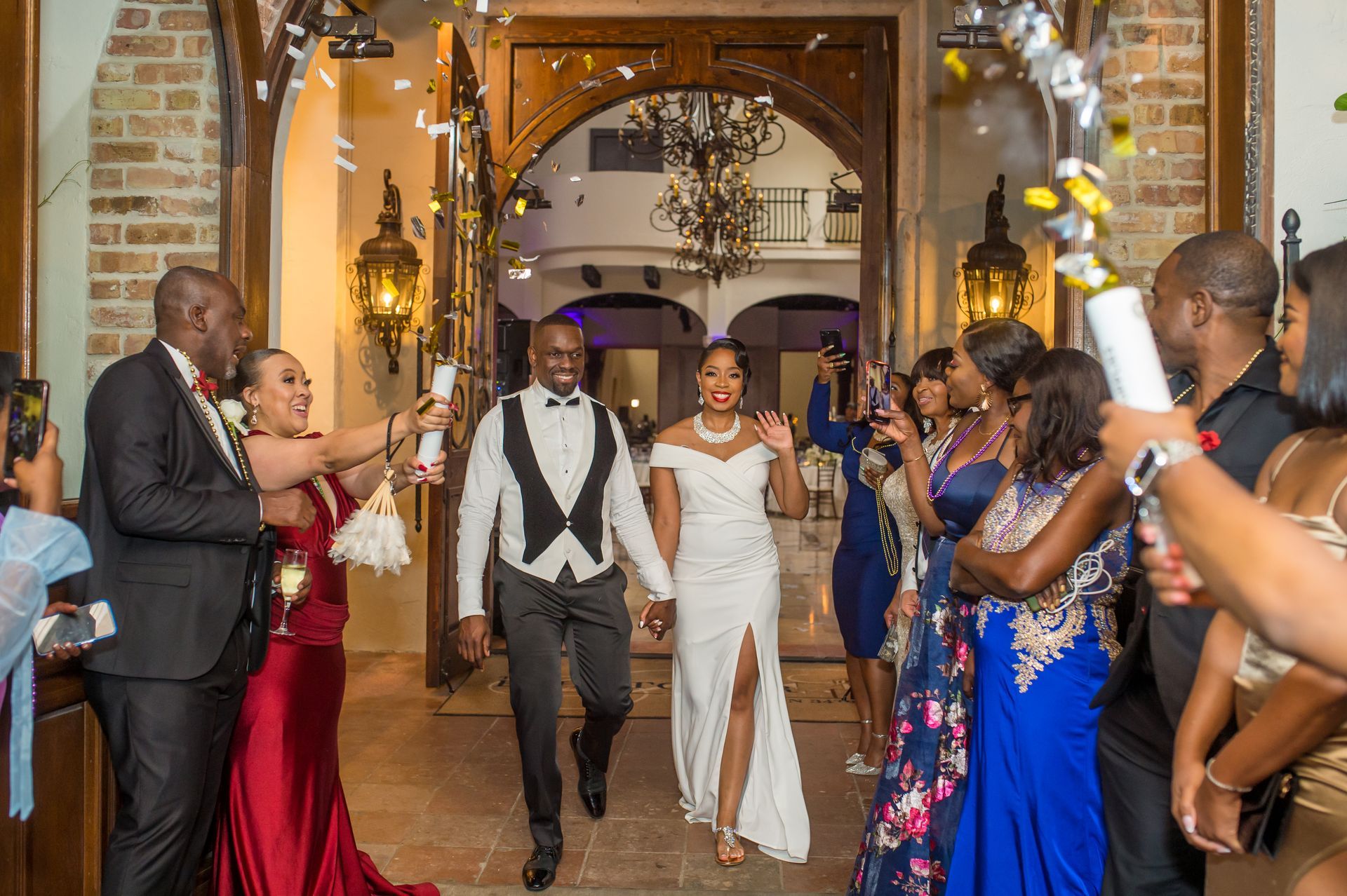 Newlyweds walk through doorway, showered with confetti by wedding guests.