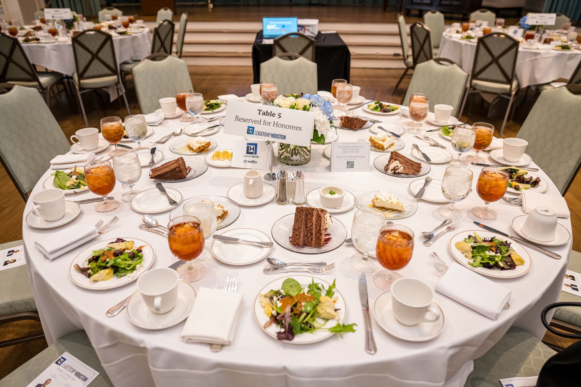Round banquet table set for a formal event with salad, cake, and beverages.