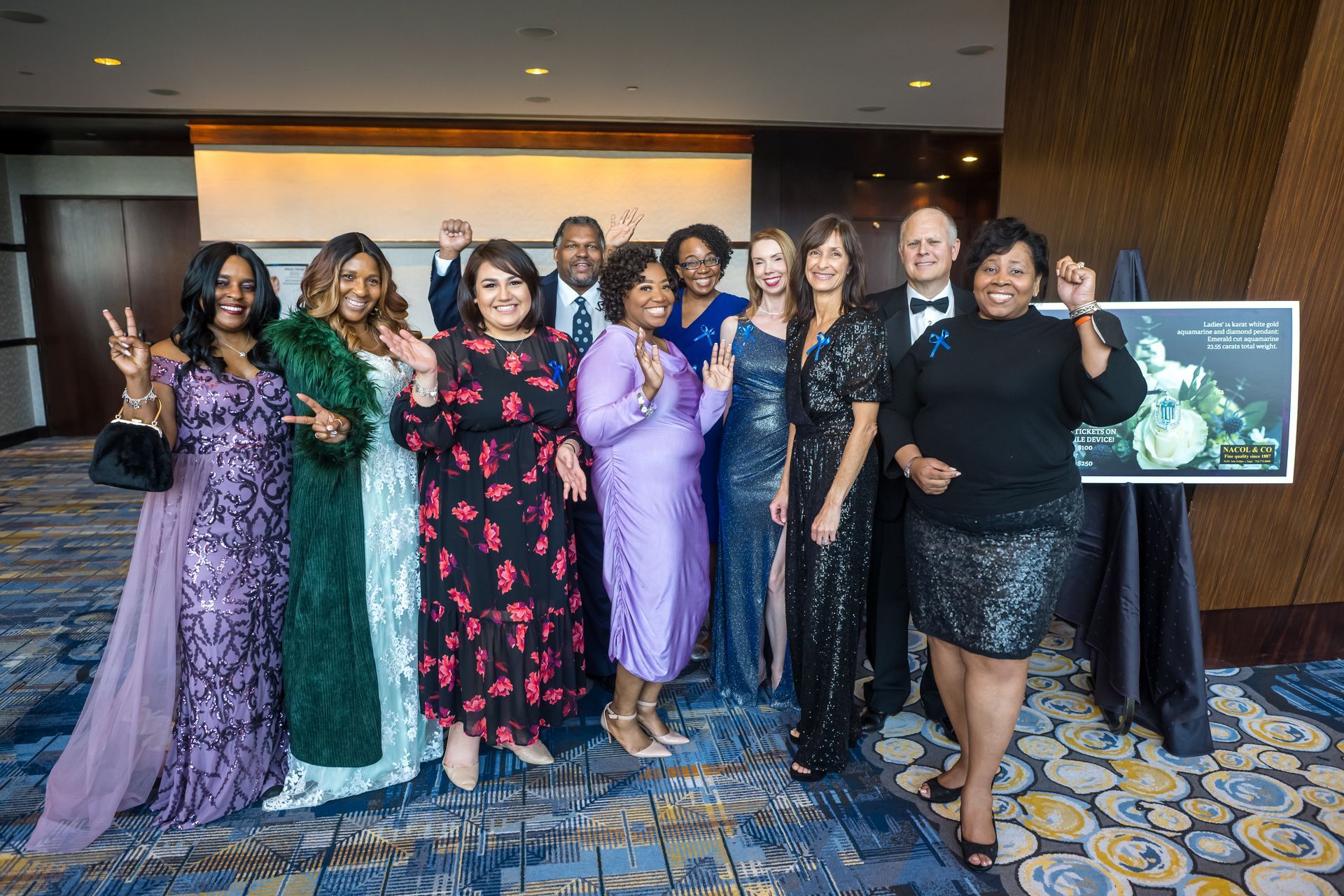 Group of people in formal attire, smiling and posing at an event.