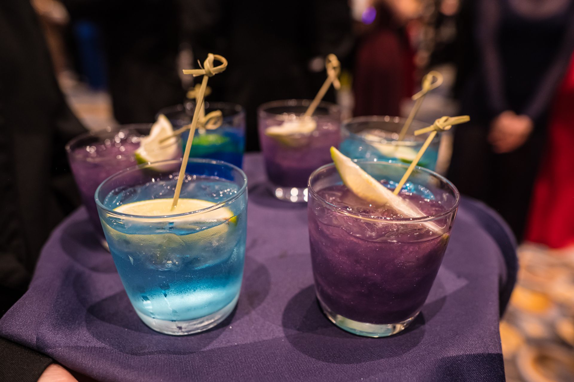 Tray of colorful cocktails with fruit garnishes.