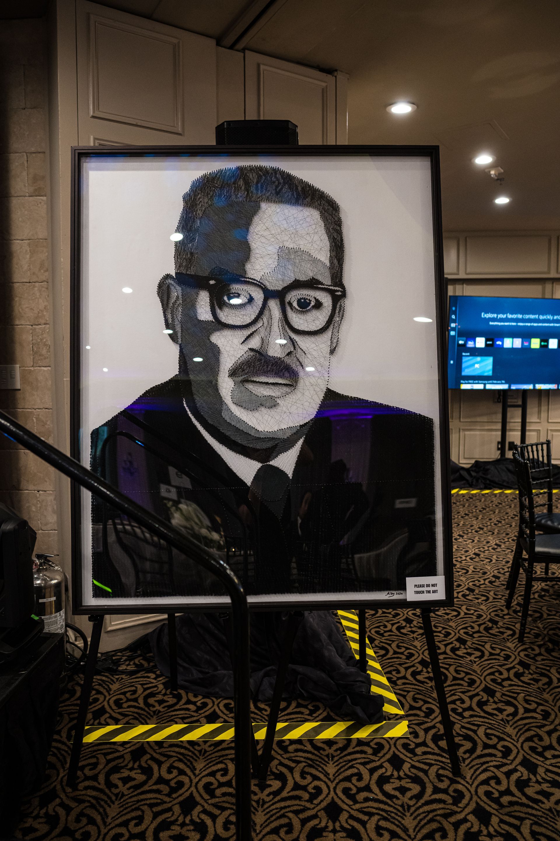 Lego portrait of a man in glasses, on display at an event. Black and white bricks form the image.