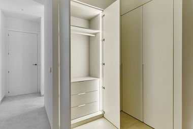 Opened door of light up white wooden fashionable built-in wardrobe