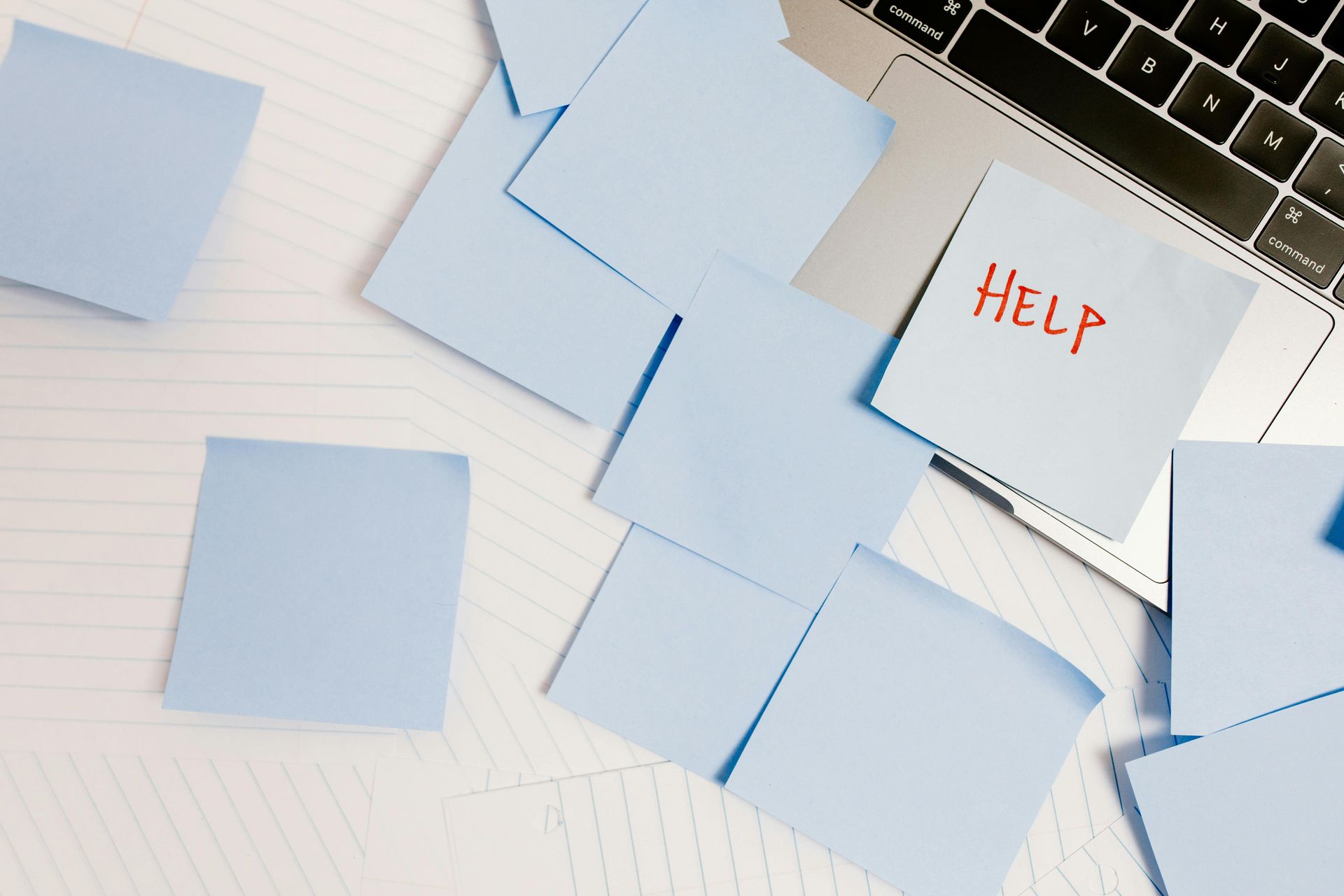 Blue sticky notes scattered around a laptop, one reads 