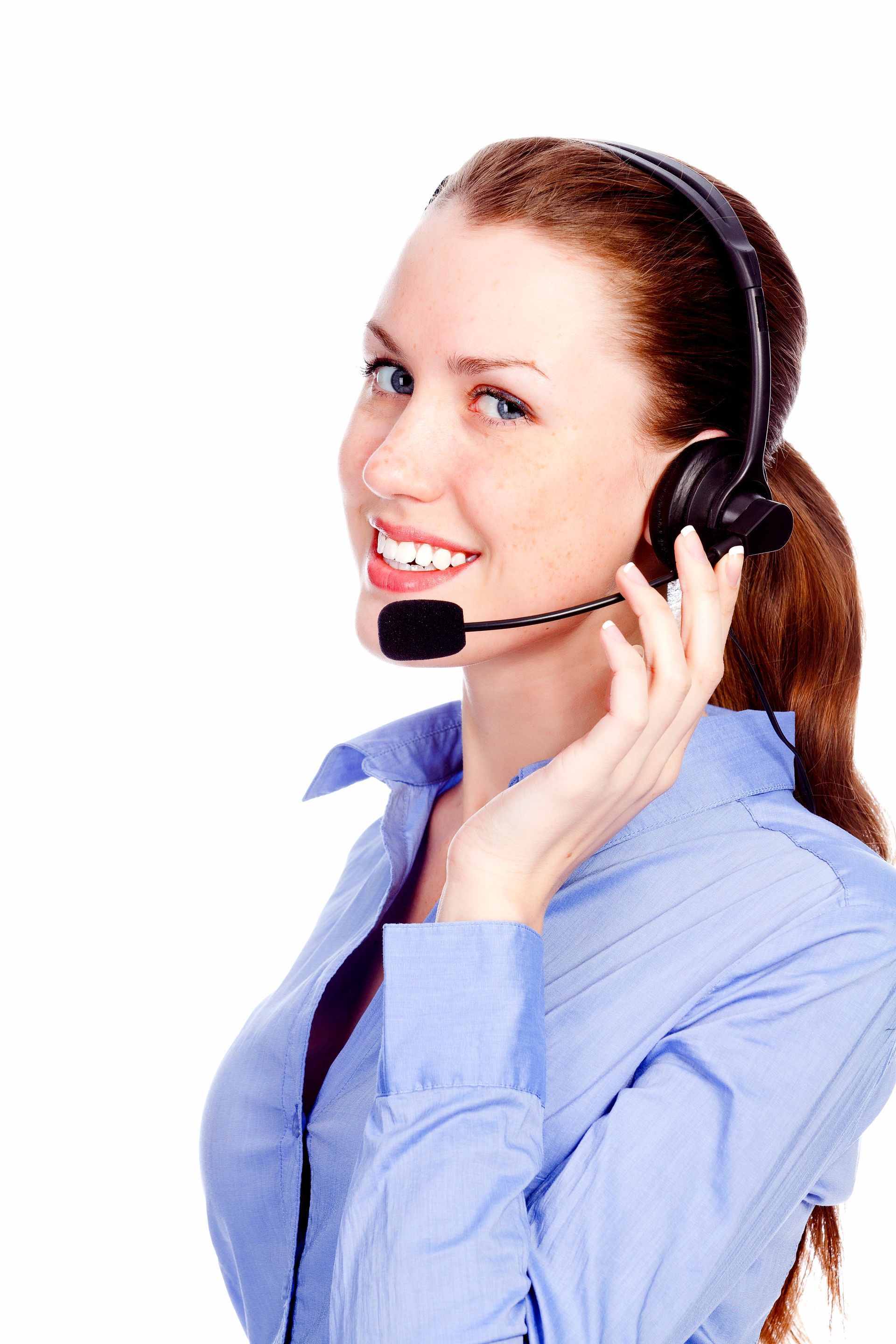 Woman with headset smiling, wearing blue shirt.