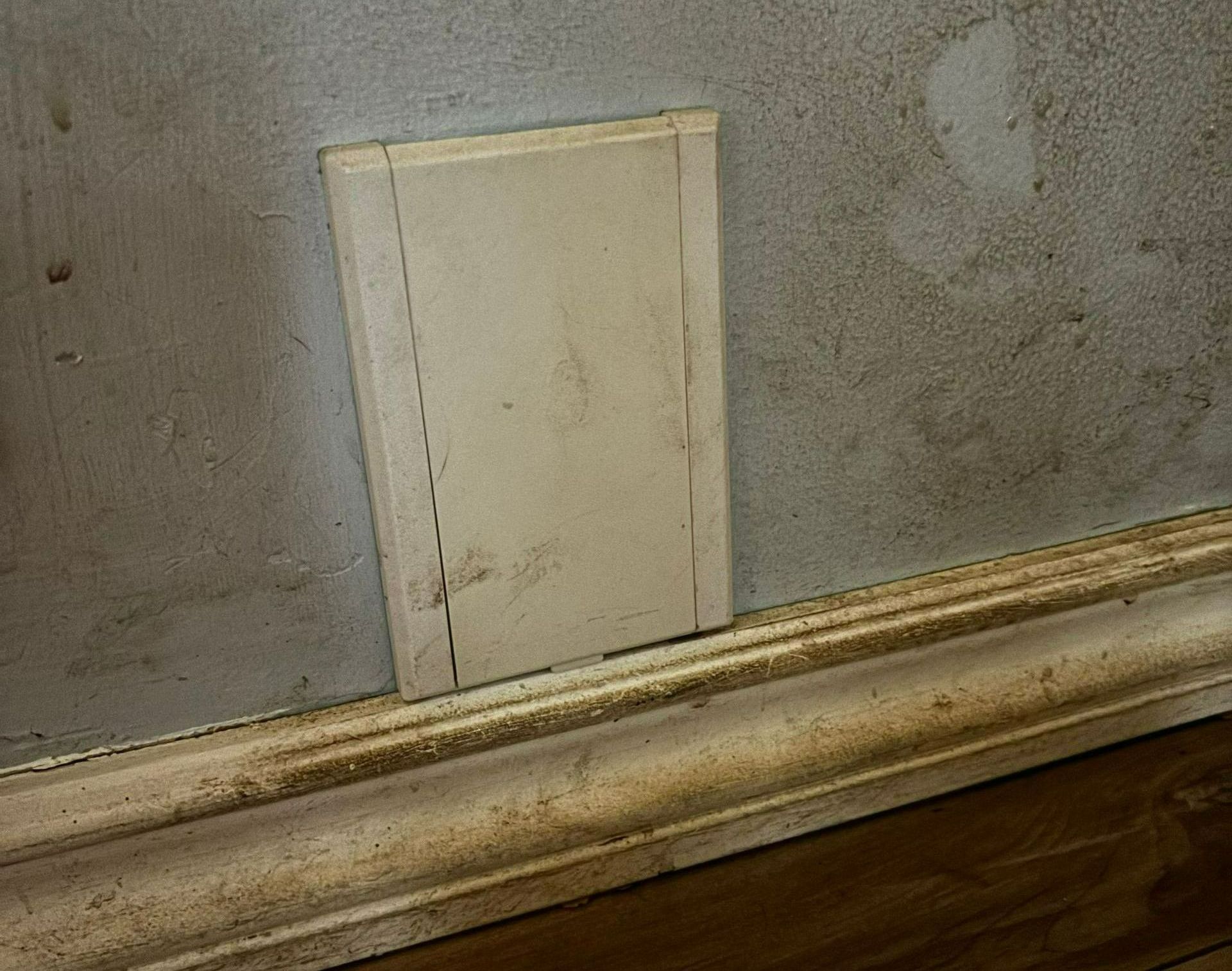 A white box is sitting on a wooden floor next to a wall.