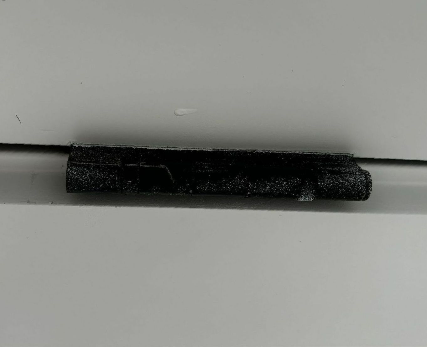 A black object is sitting on a white surface.