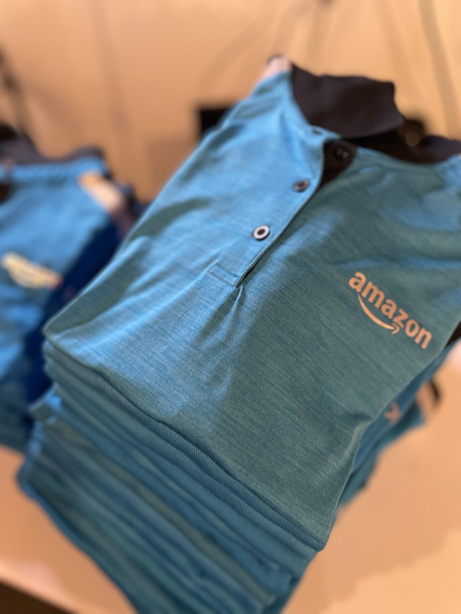 A stack of blue amazon polo shirts on a table