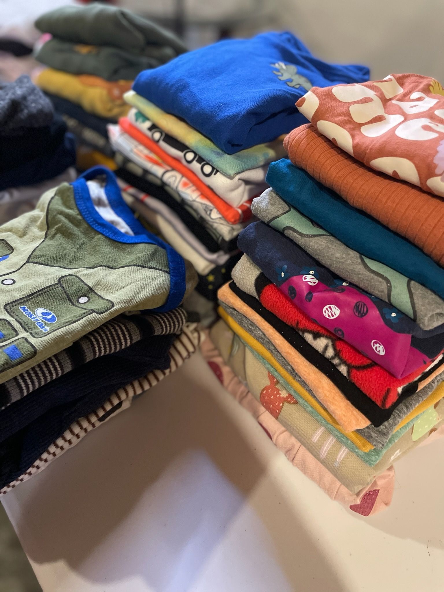 A bunch of clothes are stacked on top of each other on a table.