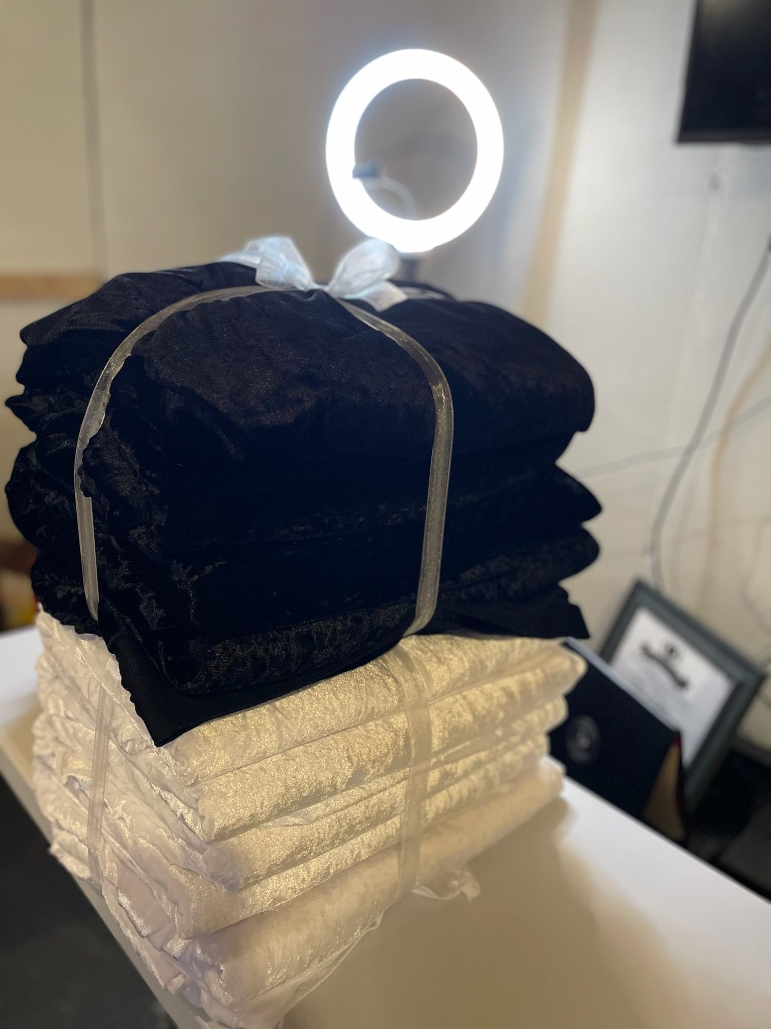 Stacks of folded black and white towels, tied together with plastic. Bright light overhead.