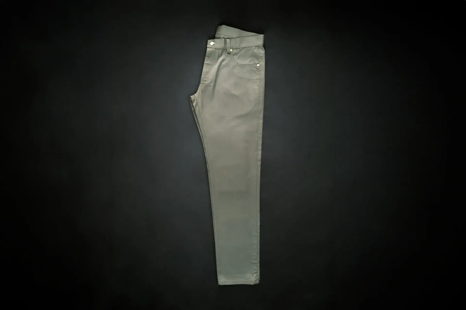 A pair of khaki pants are sitting on a black surface.