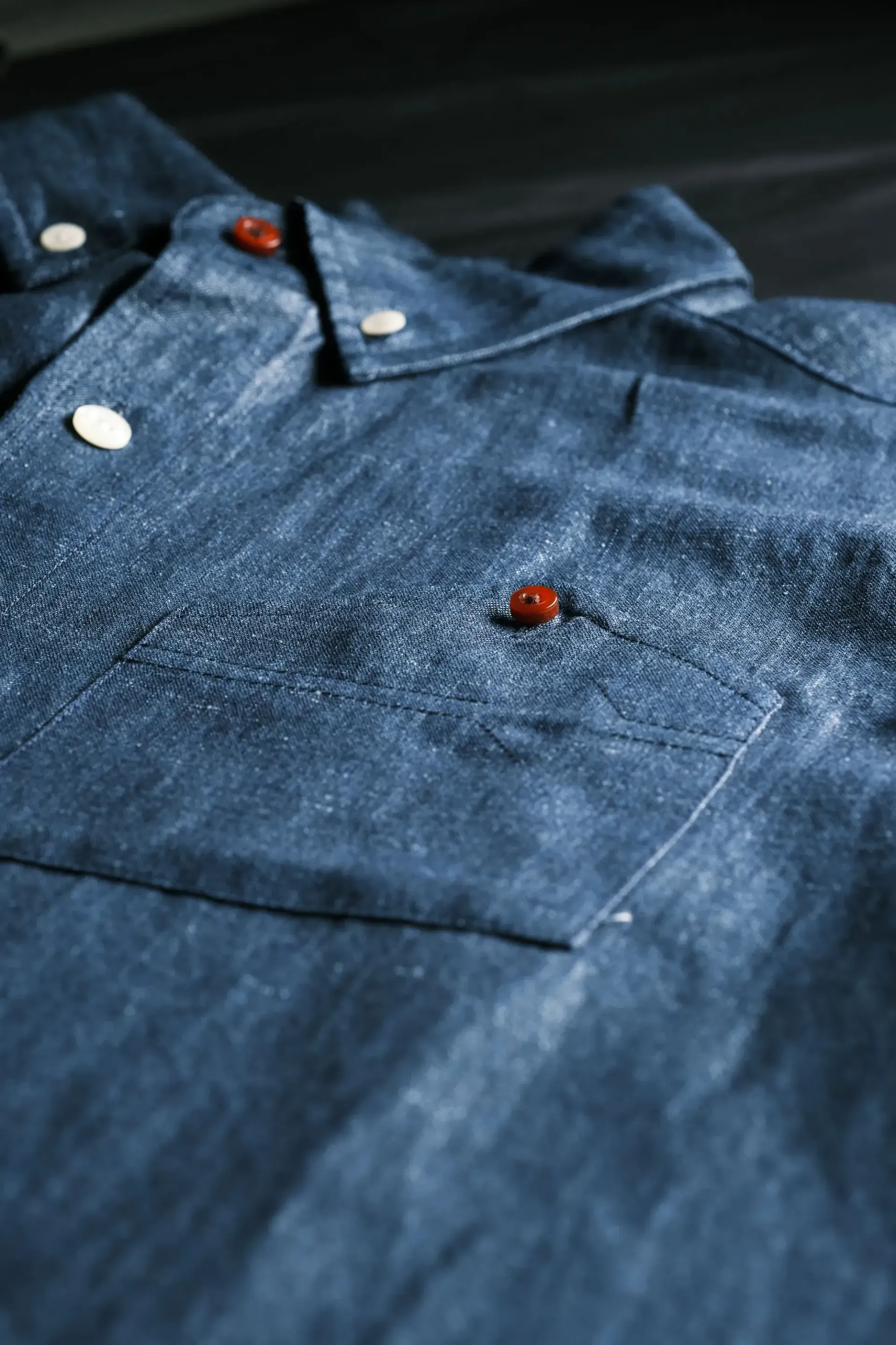 A close up of a blue shirt with red buttons on a table.
