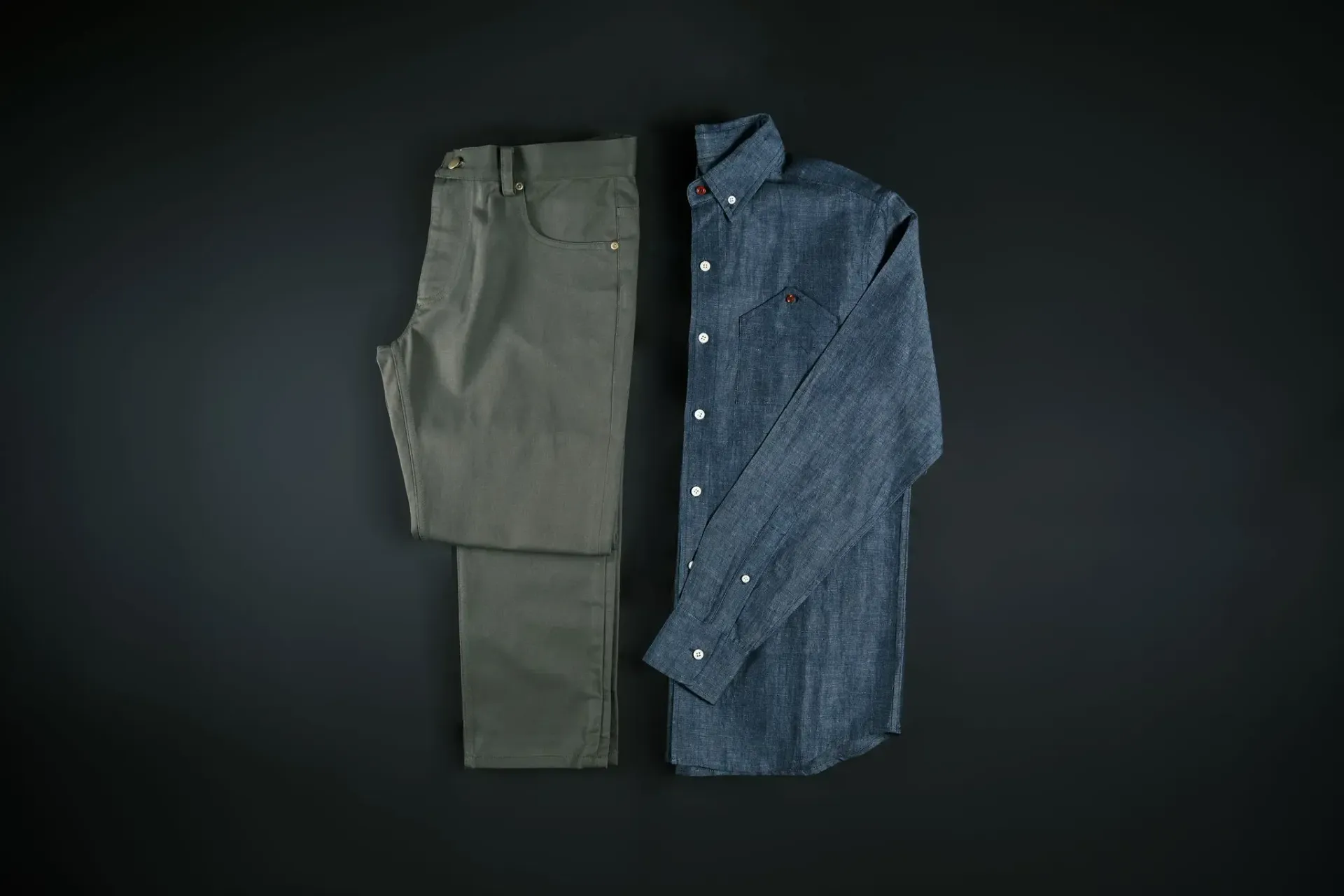 A pair of pants and a shirt are on a black surface.