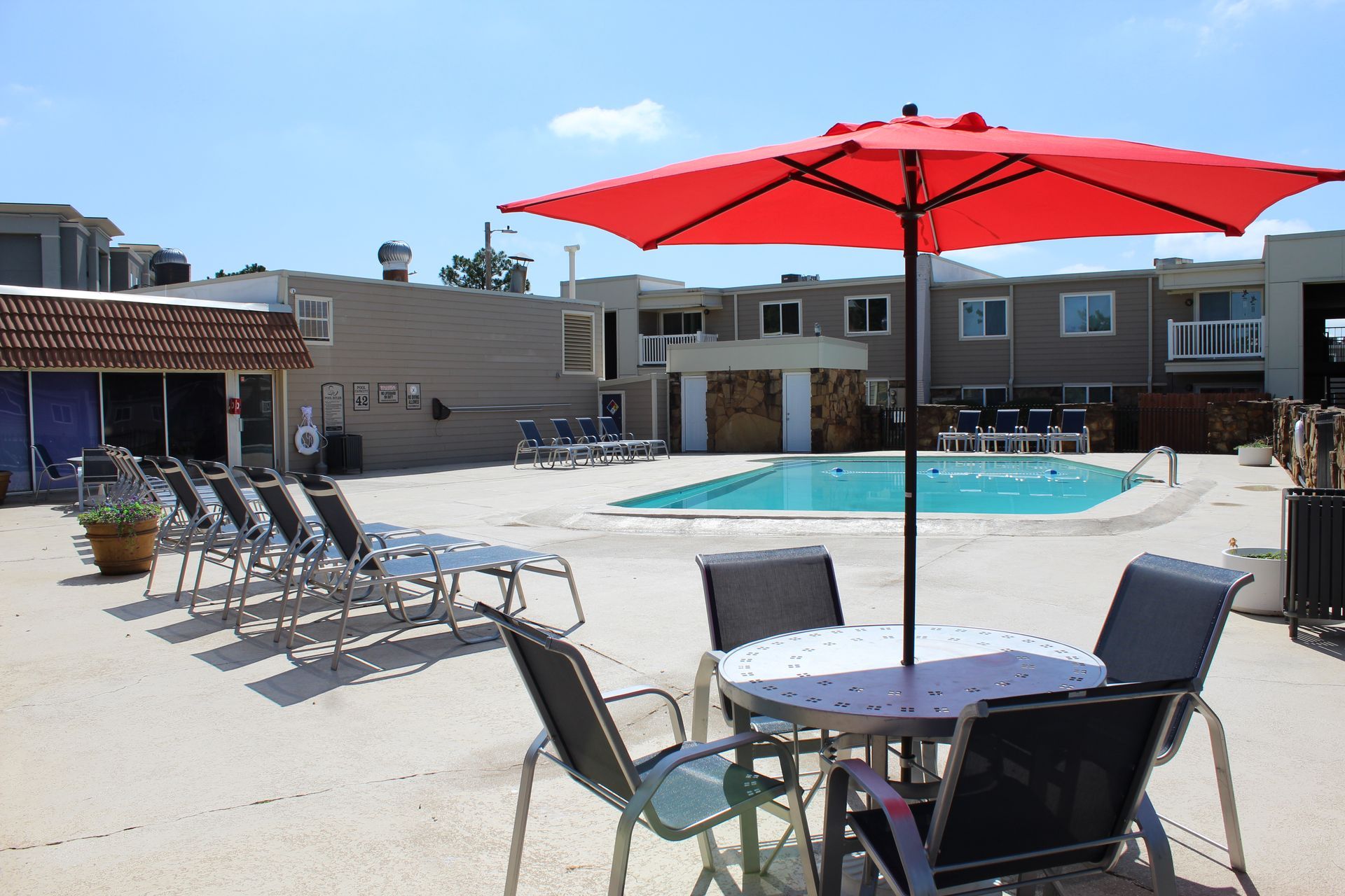 A swimming pool with a table and chairs under an umbrella