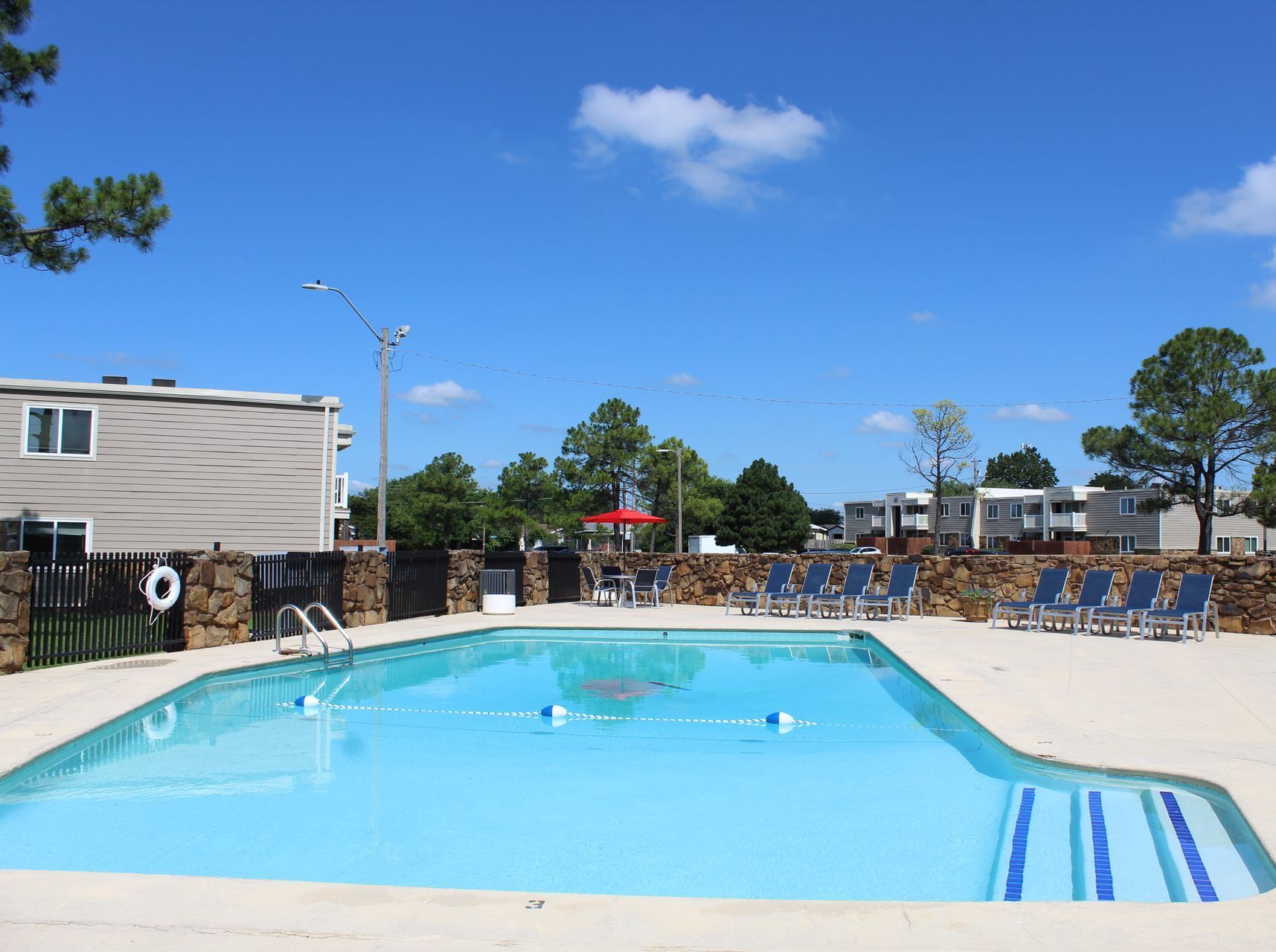 A large swimming pool surrounded by chairs and a stone wall