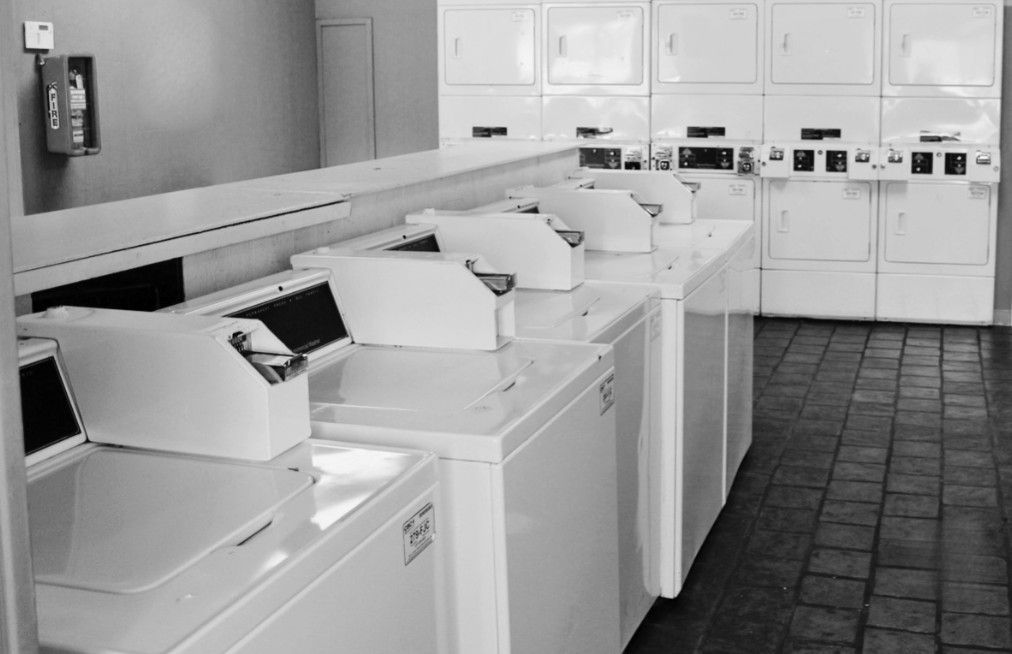 A black and white photo of a laundromat with washers and dryers
