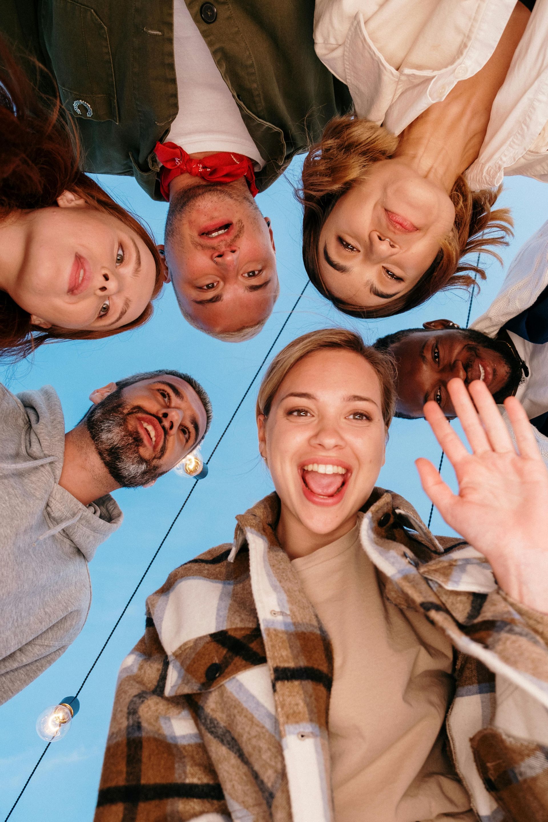A group of people are standing in a circle and waving at the camera.