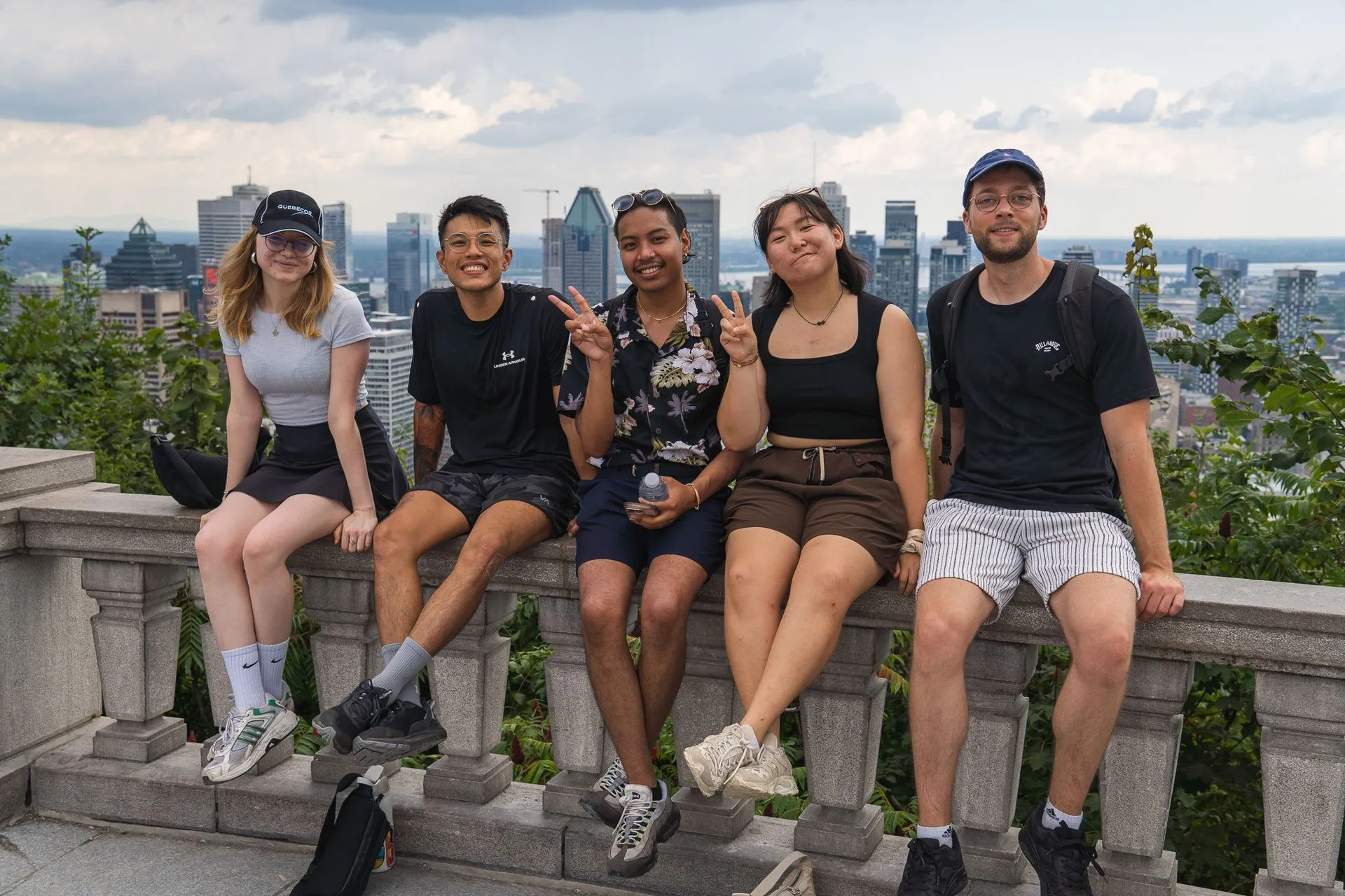 A group of people are sitting on a railing overlooking a city.