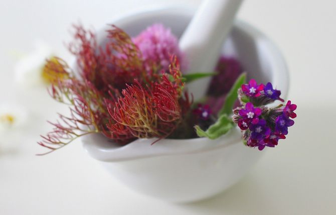 Ein mit Blumen gefüllter Mörser und Stößel auf einem Tisch.