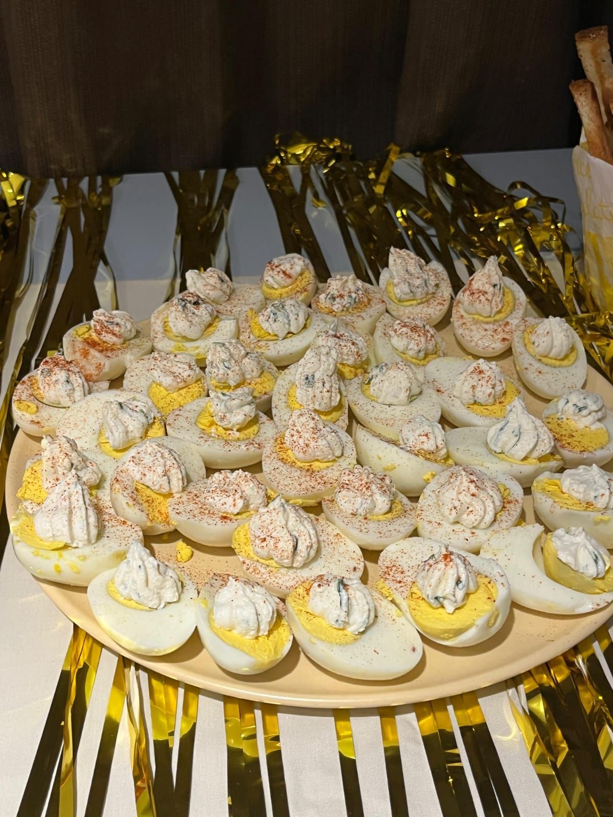 Uova alla diavola su un piatto rotondo, guarnite con paprika. Stelle filanti dorate sullo sfondo.