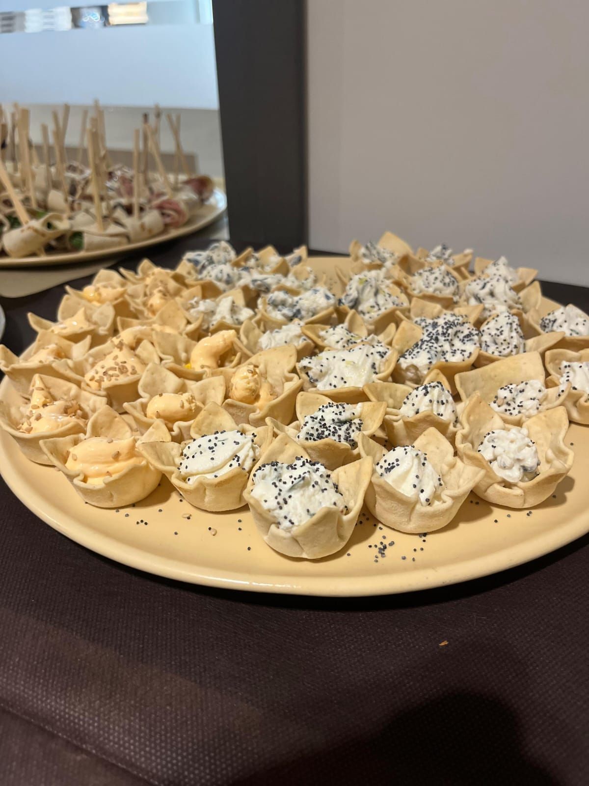 Piatto di antipasti: coppette di pasta ripiene di crema bianca e semi di papavero e un'altra con ripieno all'arancia.