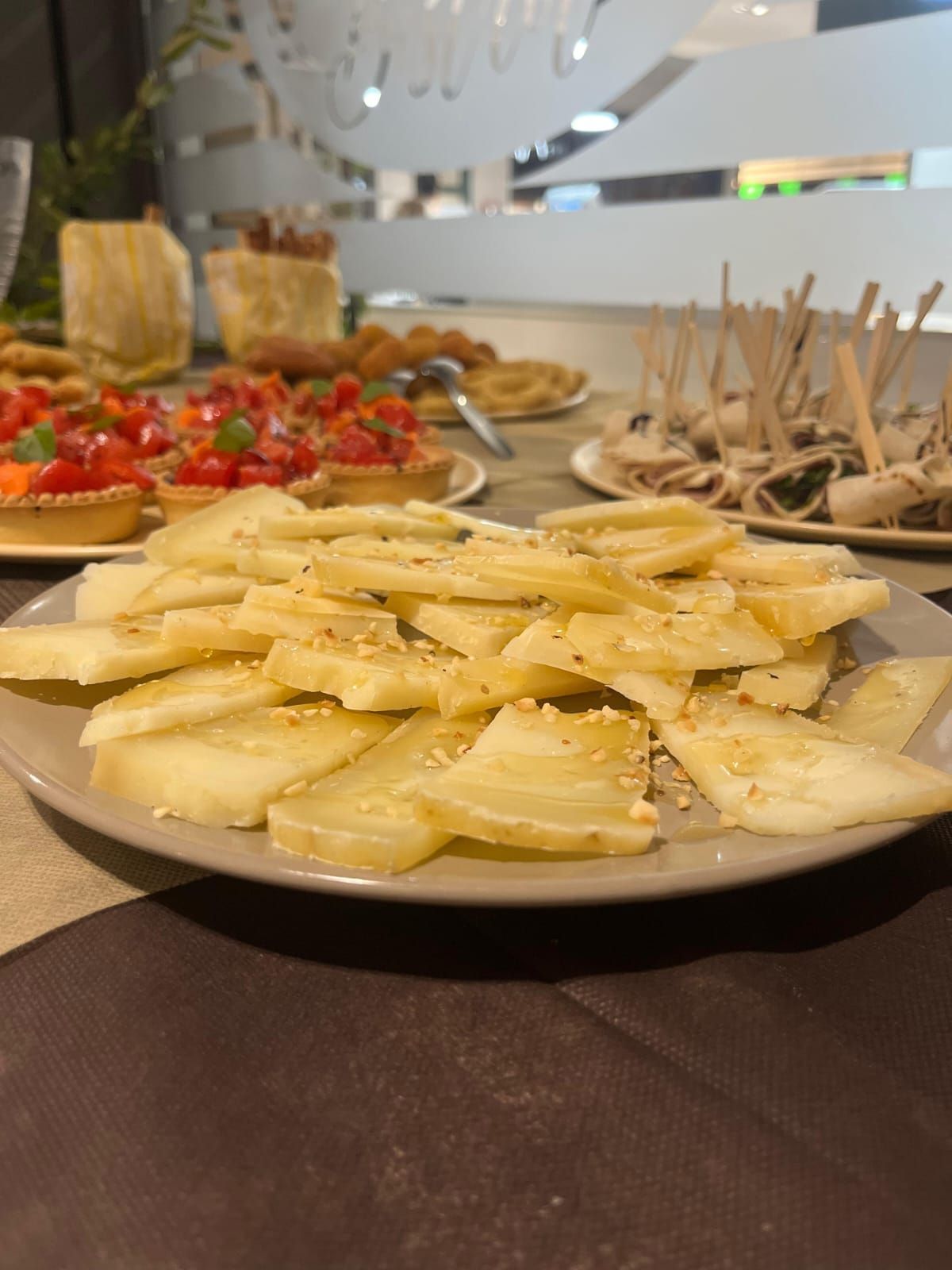 Piatto di cibo bianco a strati, cosparso di semi di sesamo, parte di un buffet.