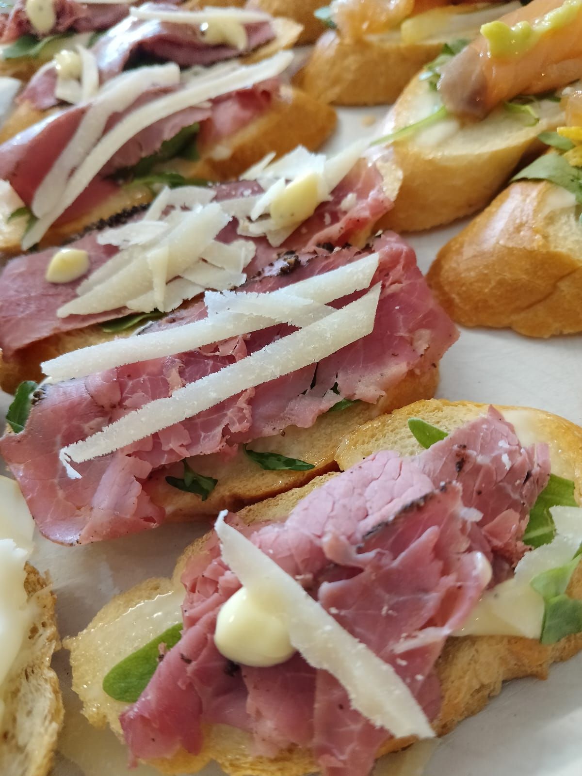 Antipasti di crostini conditi con roast beef, scaglie di formaggio ed erbe aromatiche.