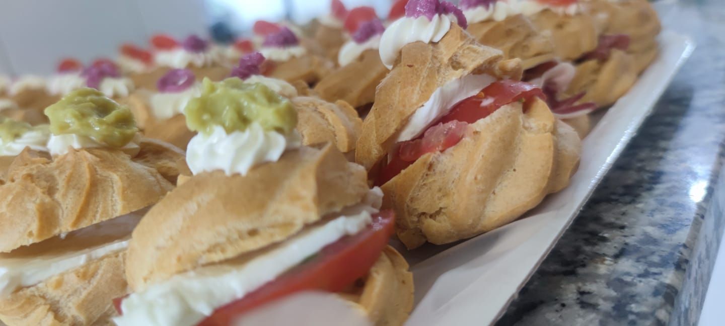 Bignè alla crema su un vassoio bianco, ripieni di panna e guarniti con frutta e guarnizione verde.