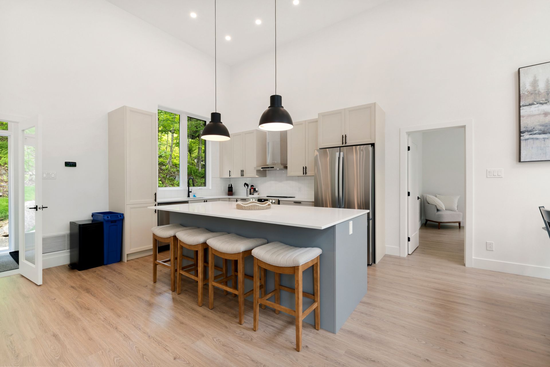 Cuisine moderne avec îlot central et tabourets de bar, parquet clair et hauts plafonds.