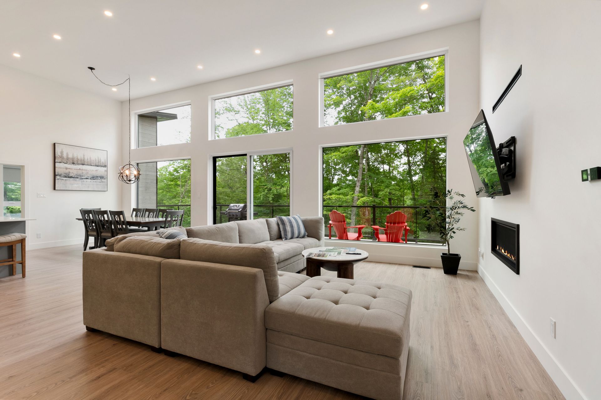 Salon moderne avec canapé d'angle, grandes fenêtres et cheminée.