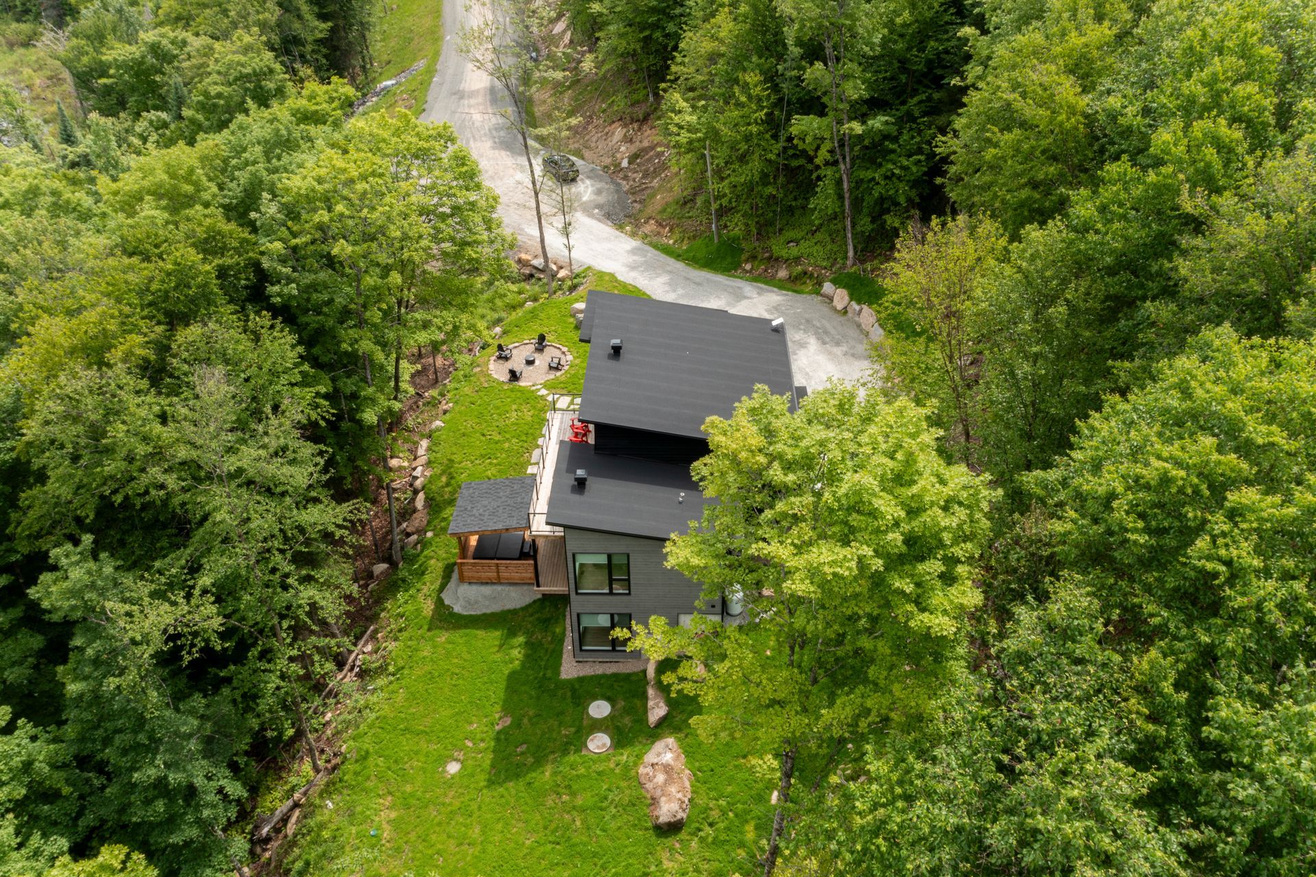 Maison moderne nichée dans une végétation luxuriante, avec un toit et une allée sombres.