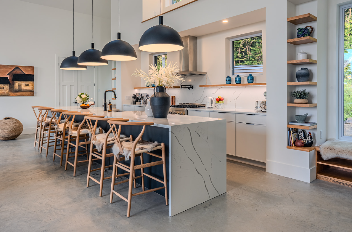 Cuisine moderne avec un grand îlot central, des suspensions lumineuses et des tabourets de bar en bois.