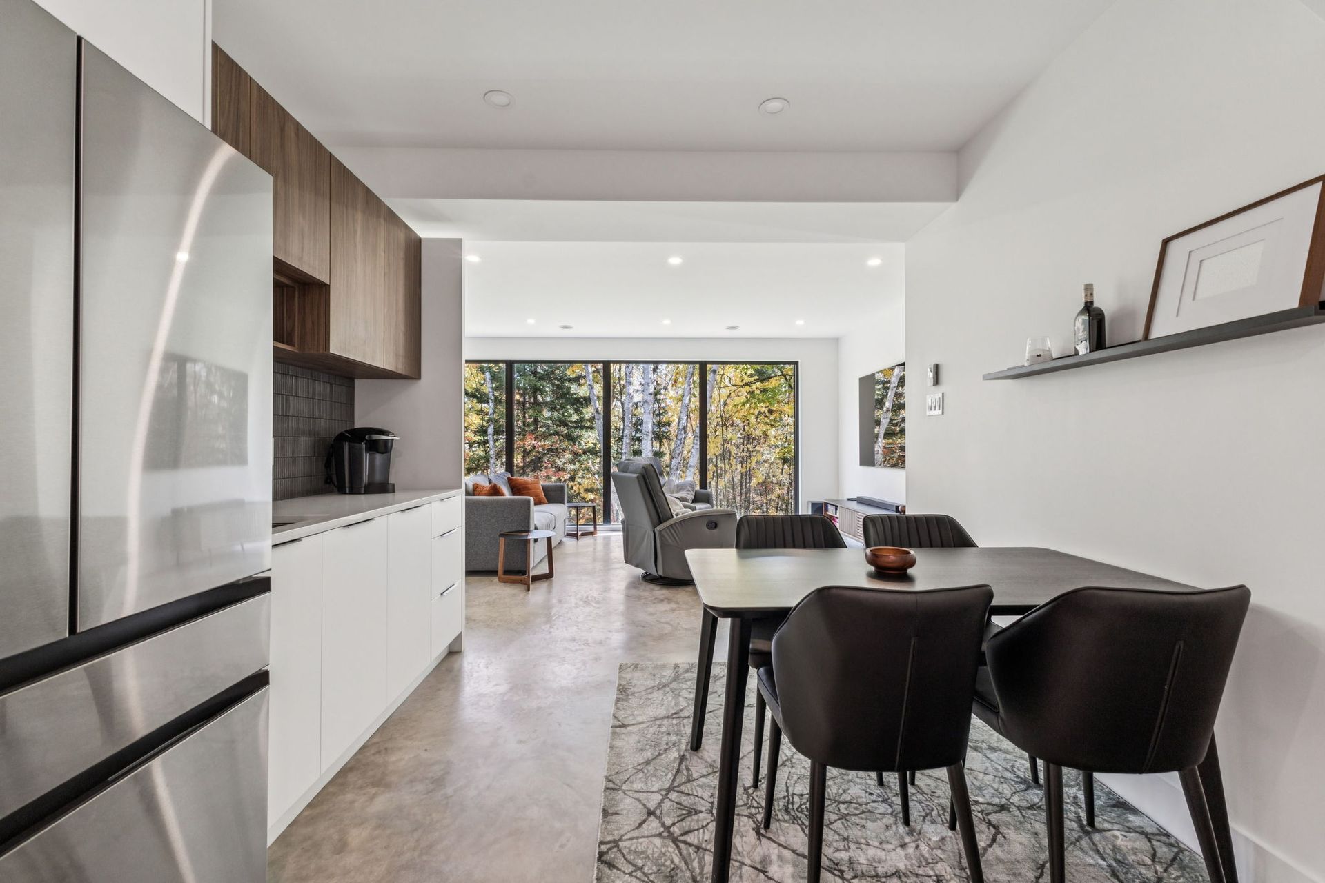 Cuisine et coin repas modernes avec réfrigérateur en acier inoxydable et chaises foncées.