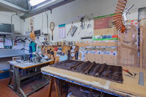 Un laboratorio luminoso con un banco da lavoro, pellicce, attrezzatura da cucito, utensili e opere d'arte appese alle pareti.