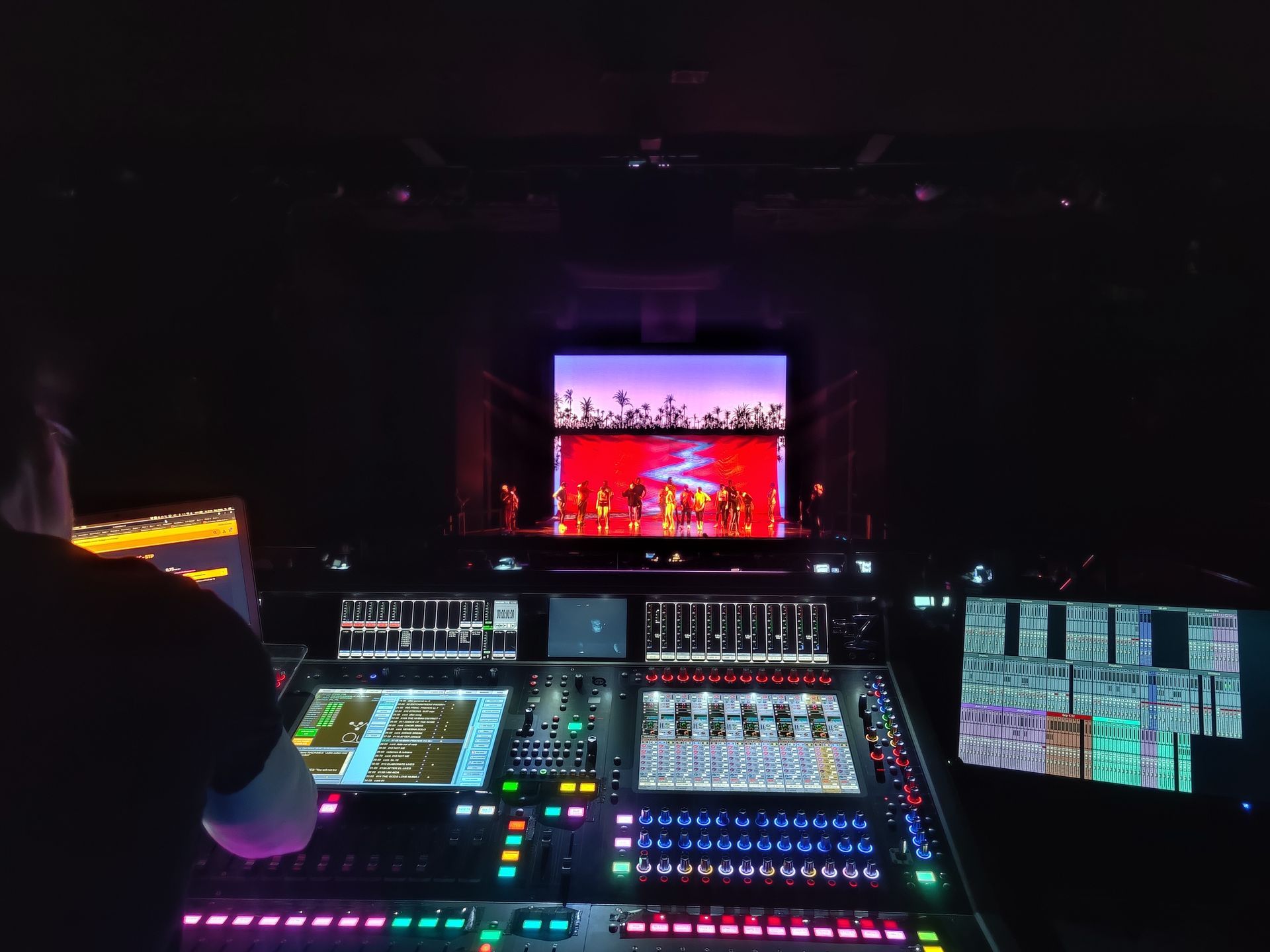 Een man zit voor een mixer in een theaterzaal.